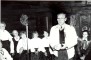 Dzejnieks Jāzeps Osmanis Braku saimes istabā ar Ērgļu tradīciju ansambļa dalībniecēm. Pa labi vadītāja Laila Kalniņa. 1992.gada 23. septembrī.

