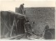 : 

Jaunās ķieģeļu ēkas būve Brakos. Sastatnes, strādā 4 strādnieki, pa labi stāv Jānis Ķirškalns, Braku muzeja pārzinis.1959.- 1960. gadi.
 